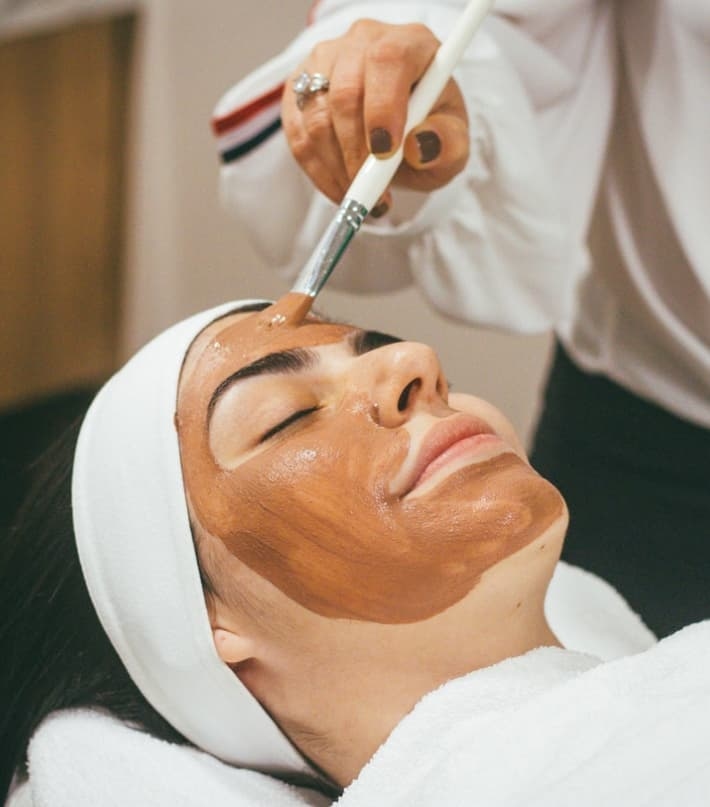 Mulher fazendo tratamento facial com um pincel